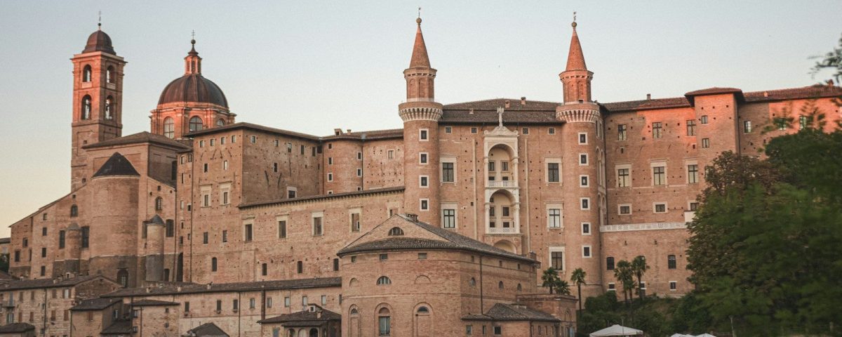 a large building with a dome on top with Urbino in the background