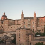 a large building with a dome on top with Urbino in the background
