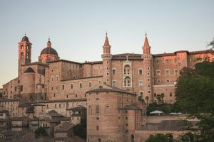 a large building with a dome on top with Urbino in the background