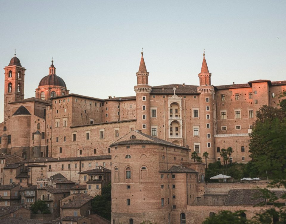 a large building with a dome on top with Urbino in the background